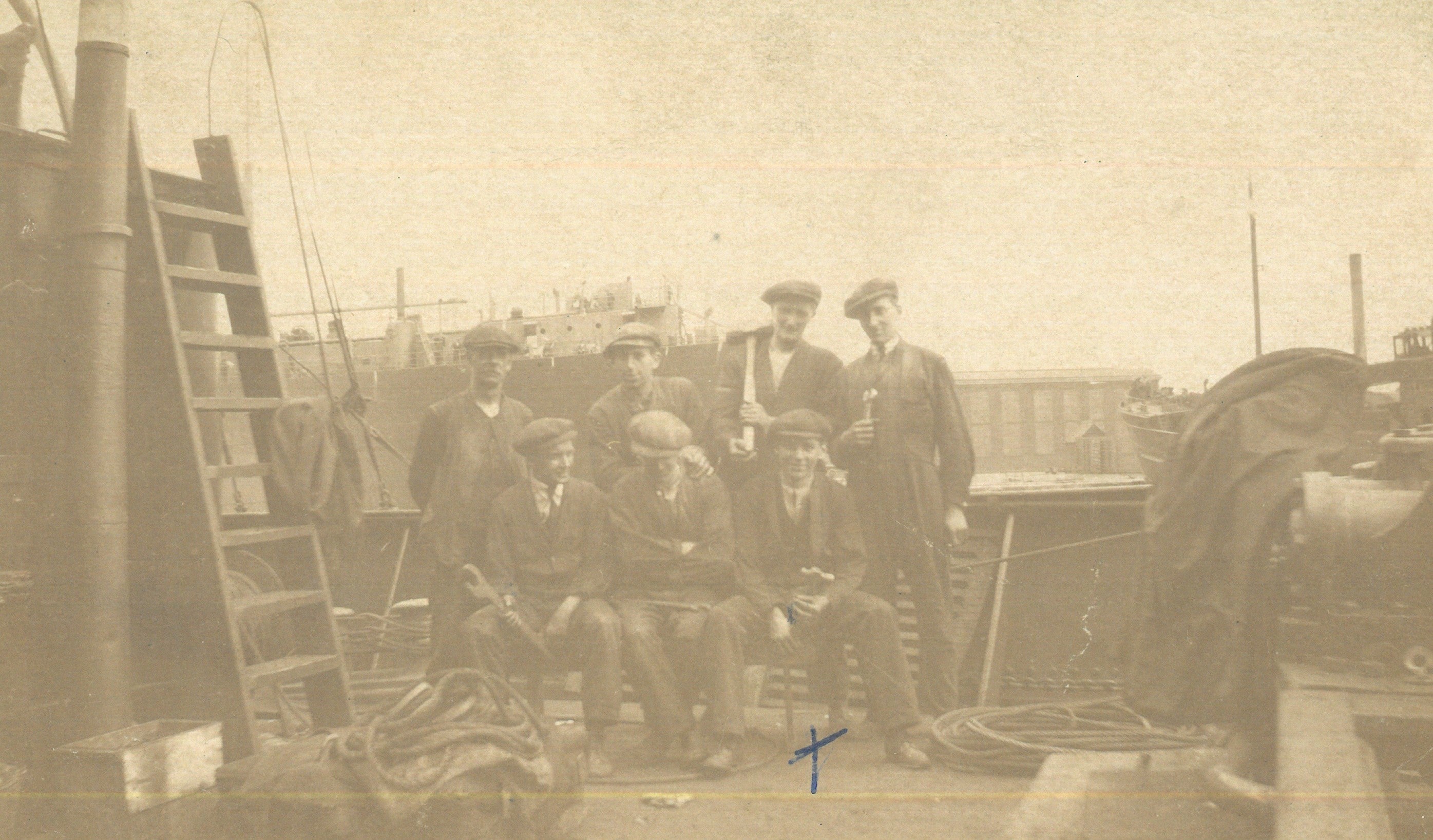 Employees pose and smile for a group photograph on the deck of one of the ships being repaired in the docks.
