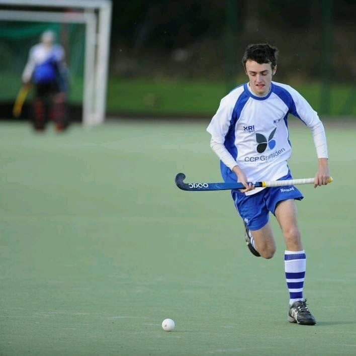 A Newcastle Nomads hockey player dribbles the ball up the pitch at speed.
