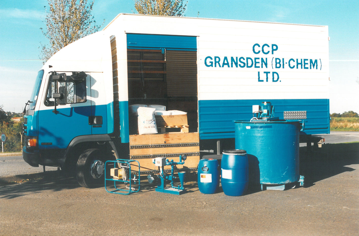One of CCP Gransden's lorries in the 1980's, painted white and blue and with CCP Gransden written on the side. Several drums sit in front of the lorry.