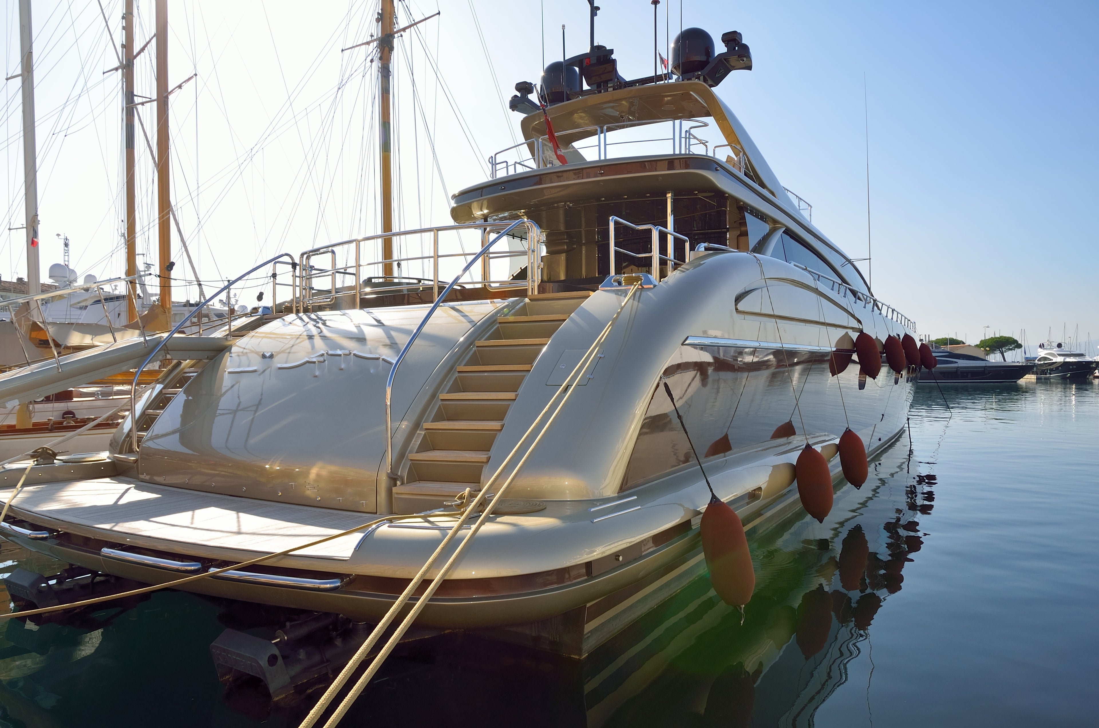 A luxury yacht sits in a sunny harbour. It has composite radomes on board.